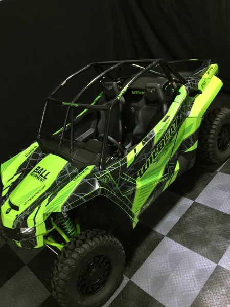 A Arctic Cat Wildcat XX side-by-side with a green, black, and dark gray Fractal custom vinyl wrap.