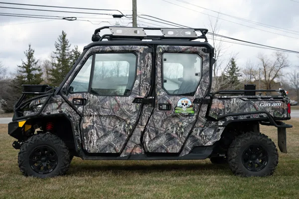 A Can-Am Defender Max side-by-side with a real tree camouflage pattern custom vinyl wrap.