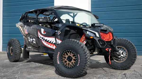 A Can-Am Maverick X3 Max side-by-side with a black, tan, and red tiger shark plane custom vinyl wrap.