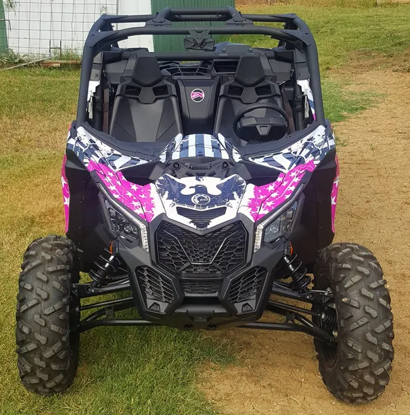 A Can-Am Maverick X3 side-by-side with a pink, white, and black grunge American Flag custom vinyl wrap.