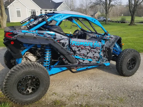 A Can-Am Maverick X3 side-by-side with a blue, black, and red skull Demonic custom vinyl wrap.