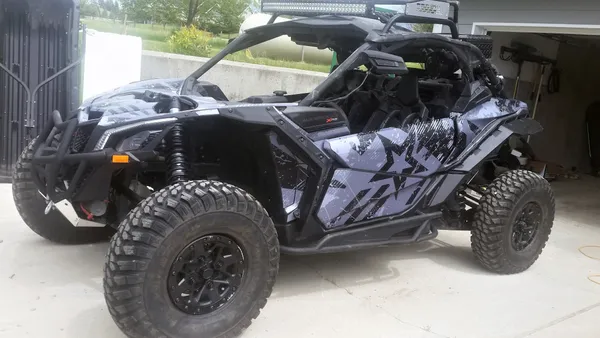 A Can-Am Maverick X3 side-by-side with a black and dark gray grunge Wartorn custom vinyl wrap.