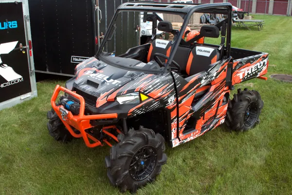 A Polaris Ranger 2 Door side-by-side with a black and orange Theut custom vinyl wrap.