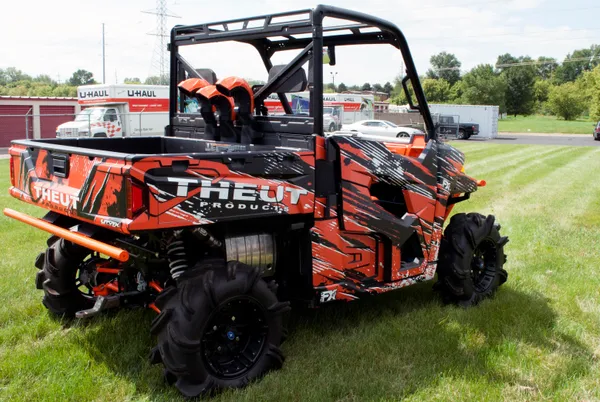 A Polaris Ranger 2 Door side-by-side with a black and orange Theut custom vinyl wrap.