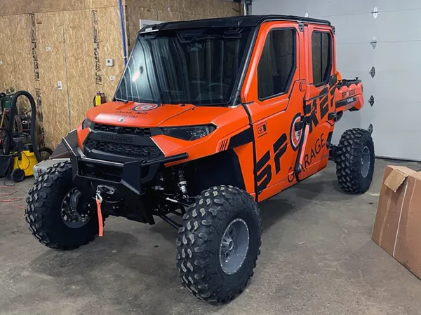 A Polaris Ranger 4 Door side-by-side with an orange and black custom vinyl wrap.