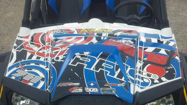 A Polaris RZR 2 Door side-by-side with a blue, black, and red  custom vinyl wrap.