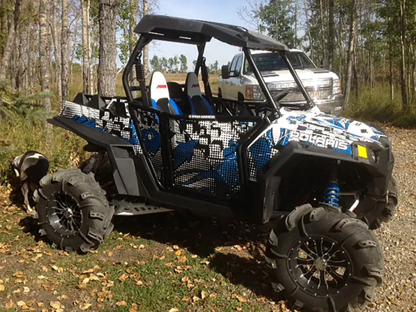 A Polaris RZR 2 Door side-by-side with a blue and white Instinct custom vinyl wrap.