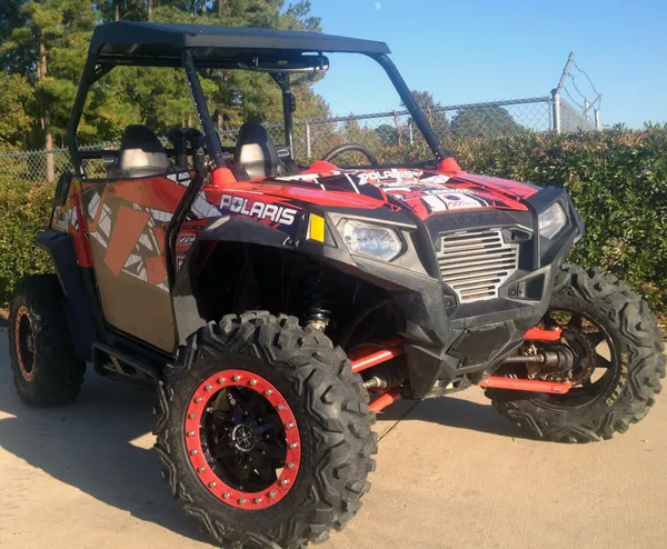 A Polaris RZR 2 Door side-by-side with a red and white Panzer custom vinyl wrap.