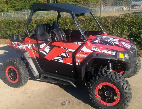 A Polaris RZR 2 Door side-by-side with a red and white Instinct custom vinyl wrap.