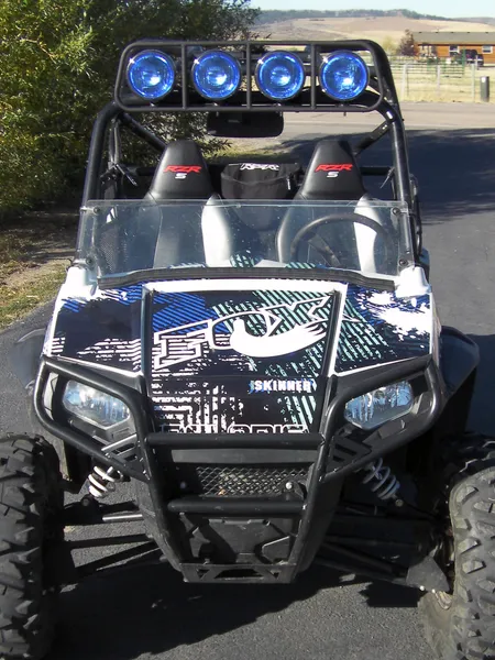 A Polaris RZR 2 Door side-by-side with a blue and white Point Blank custom vinyl wrap.