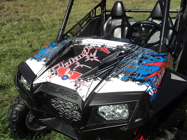 A Polaris RZR 2 Door side-by-side with a red, white and blue Retrobution custom vinyl wrap.