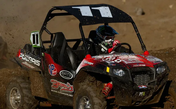 A Polaris RZR 2 Door side-by-side with a red and white Action custom vinyl wrap.