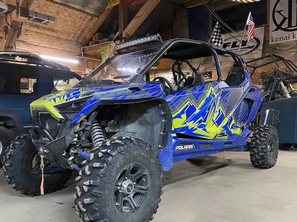 A Polaris RZR PRO XP 2 Door side-by-side with a lime squeeze, blue, and gray grunge mountain Altitude custom vinyl wrap.
