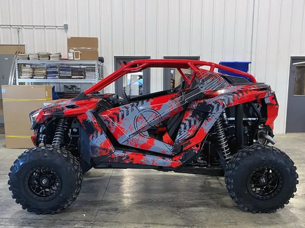 A Polaris RZR PRO XP 2 Door side-by-side with a red, black, and gray grunge Bombsquad custom vinyl wrap.