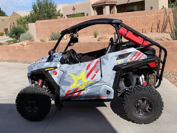 A Polaris RZR Trail 2 Door side-by-side with a gray, lime squeeze, and red grunge Wartorn custom vinyl wrap.