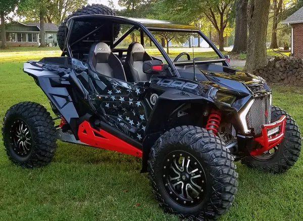A Polaris RZR XP 2 Door 2018+ side-by-side with a red, black, and gray grunge American Flag custom vinyl wrap.