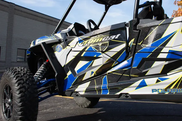 A Polaris RZR XP 4 Door 2018+ side-by-side with a lime squeeze, black, blue, and gray geometric triangle design Ascension custom vinyl wrap.
