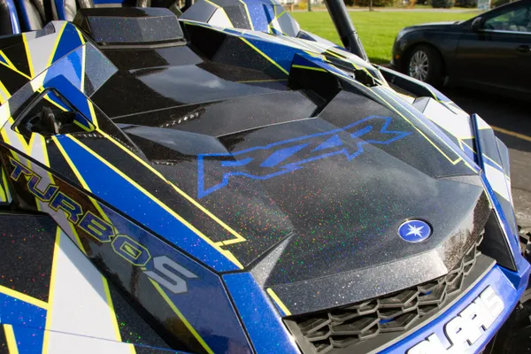 A Polaris RZR XP 4 Door 2018+ side-by-side with a lime squeeze, black, blue, and gray geometric triangle design Ascension custom vinyl wrap.