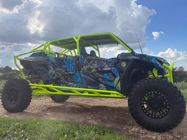 A Polaris RZR XP 4 Door 2018+ side-by-side with a black, lime squeeze, and blue grunge Bombsquad custom vinyl wrap.
