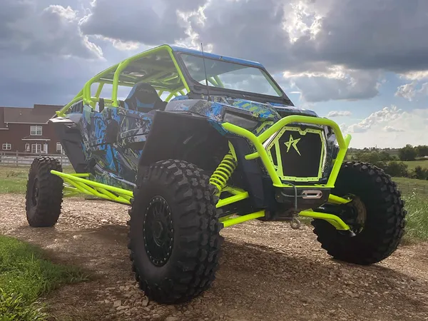 A Polaris RZR XP 4 Door 2018+ side-by-side with a black, lime squeeze, and blue grunge Bombsquad custom vinyl wrap.