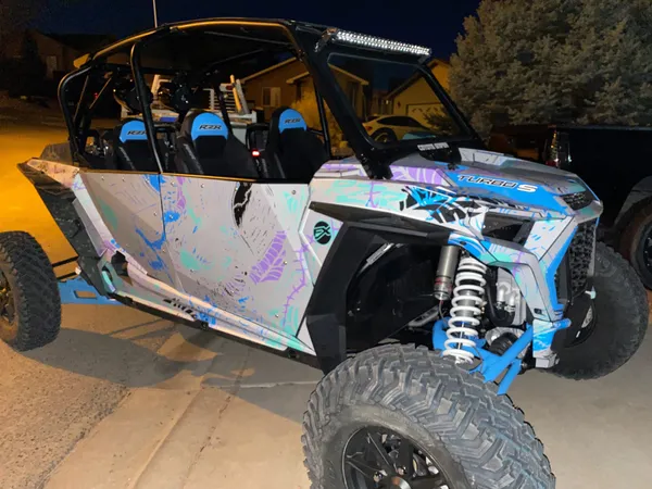 A Polaris RZR XP 4 Door 2018+ side-by-side with a gray, blue, and purple sketch grunge Braap Attack custom vinyl wrap.