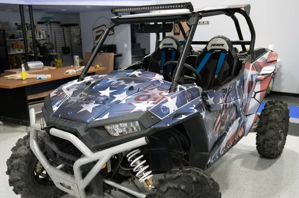 A Polaris RZR XP 2 Door side-by-side with a red, white, and blue American 911 Heroes custom vinyl wrap.