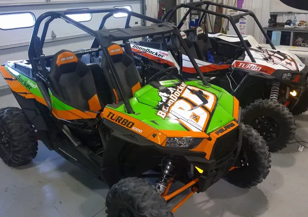 A pair of Polaris RZR XP 2 Door side-by-sides with colorful racing stripe design custom vinyl wrap.