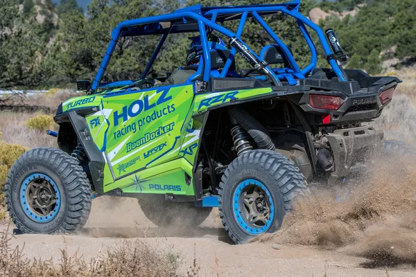 A Polaris RZR XP 2 Door side-by-side with a lime, blue, and white stripes Evolution custom vinyl wrap.