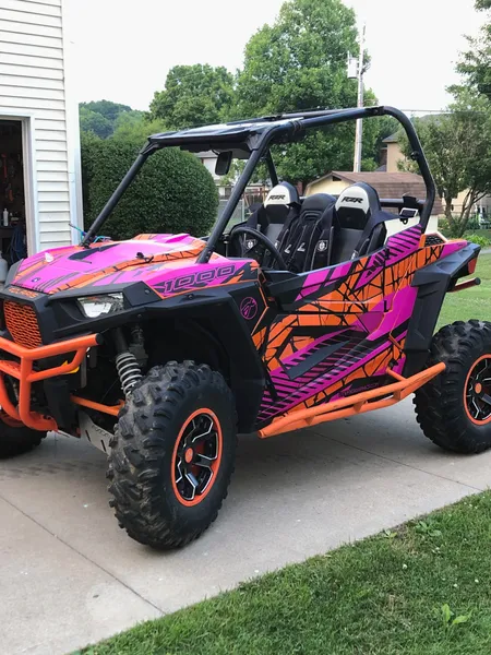A Polaris RZR XP 2 Door side-by-side with a orange, pink, and black Fractal custom vinyl wrap.