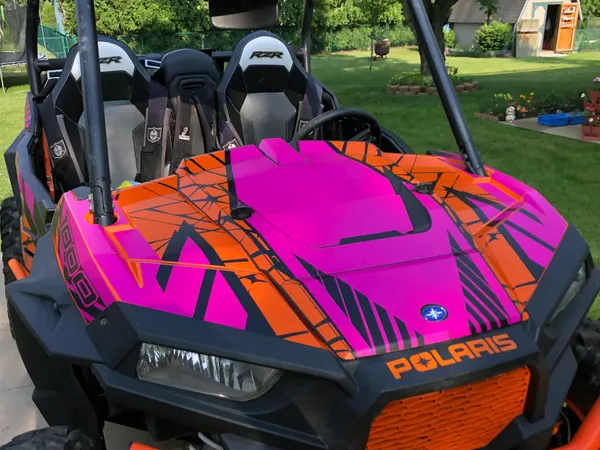 A Polaris RZR XP 2 Door side-by-side with a orange, pink, and black Fractal custom vinyl wrap.