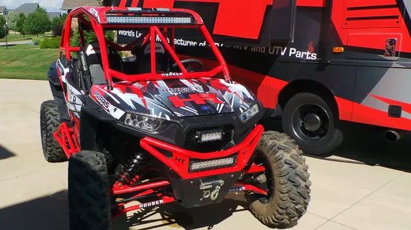 A Polaris RZR XP 2 Door side-by-side with a red, white, and black Houser Racing custom vinyl wrap.