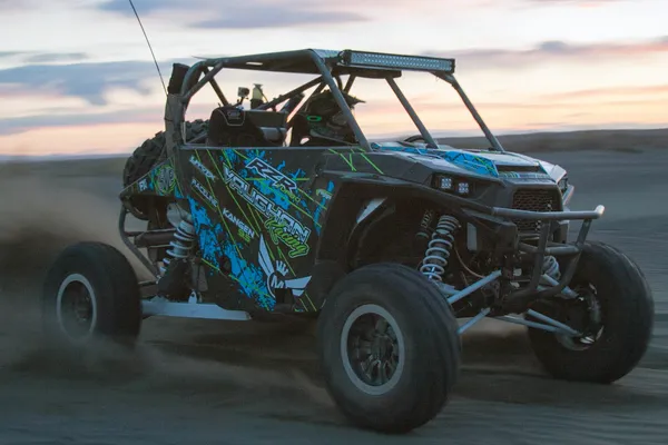 A Polaris RZR XP 2 Door side-by-side with a black, blue, and lime grunge lines Oblivion custom vinyl wrap.