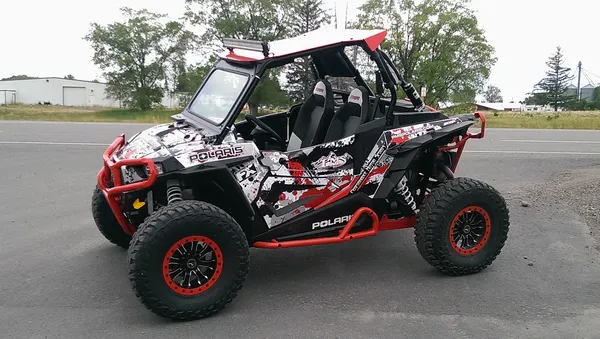 A Polaris RZR XP 2 Door side-by-side with a red, white, and black grunge paint splatter custom vinyl wrap.