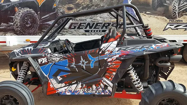 A Polaris RZR XP 2 Door side-by-side with a red, white, and blue grunge Retrobution custom vinyl wrap.
