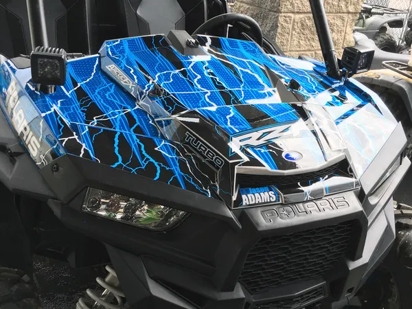 A Polaris RZR XP 2 Door side-by-side with a blue, black, and white lightning design Vitalize custom vinyl wrap.