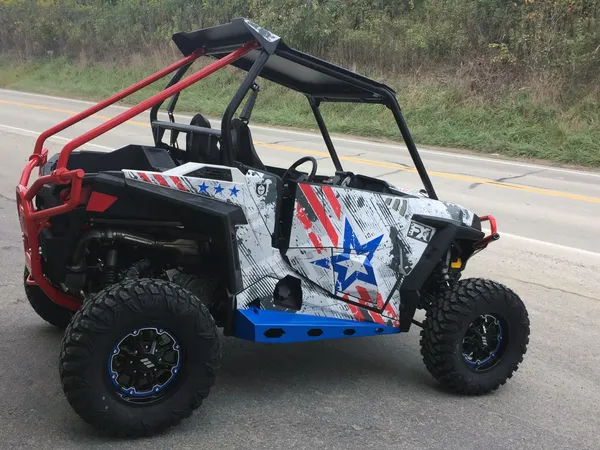 A Polaris RZR XP 2 Door side-by-side with a red, white, and blue grunge Wartorn custom vinyl wrap.