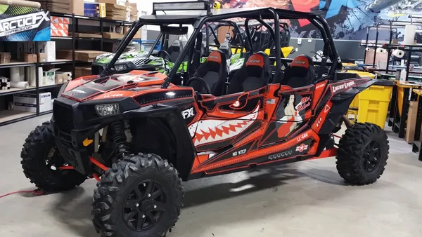 A Polaris RZR XP 4 Door side-by-side with a black, white, and orange flying sharks plane Spitfire custom vinyl wrap.