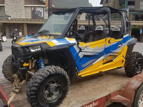 A Polaris RZR XP 4 Door side-by-side with a blue, yellow, and gray grunge stripes Pursuit custom vinyl wrap.