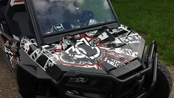 A Polaris RZR XP 4 Door side-by-side with a black, gray, and red grunge 307 Rising Sun custom vinyl wrap.
