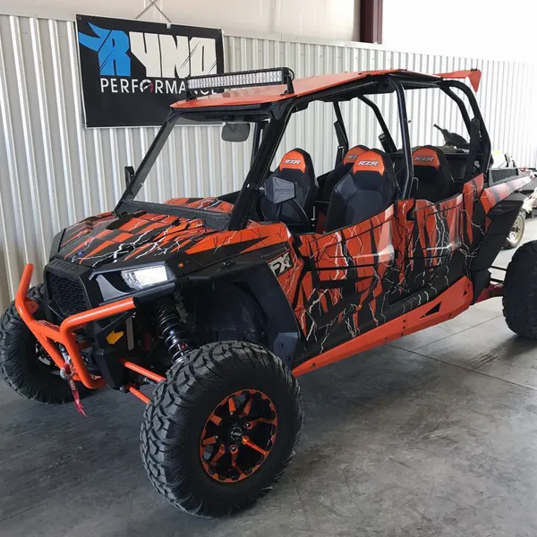 A Polaris RZR XP 4 Door side-by-side with a black, white, and orange lightning design Vitalize custom vinyl wrap.