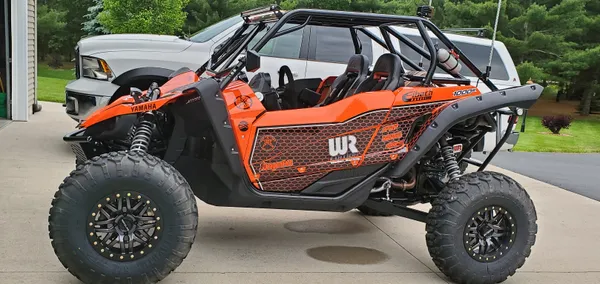 A Yamaha YXZ1000R side-by-side with a orange, black, and white striped honeycomb custom vinyl wrap.