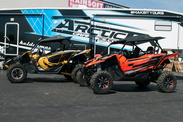 A pair of Yamaha YXZ1000R side-by-sides with a colorful unique custom vinyl wraps.