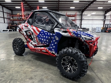 A Polaris RZR PRO XP 2 Door side-by-side with a red, white, and blue grunge American Flag custom vinyl wrap.