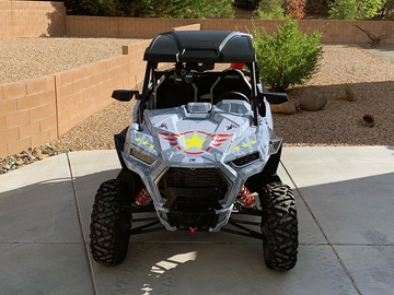 A Polaris RZR Trail 2 Door side-by-side with a gray, lime squeeze, and red grunge Wartorn custom vinyl wrap.